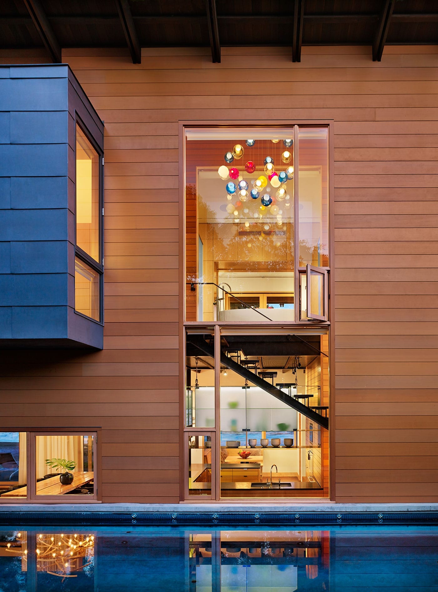 Slim wood storefront window spans levels overlooking the pool